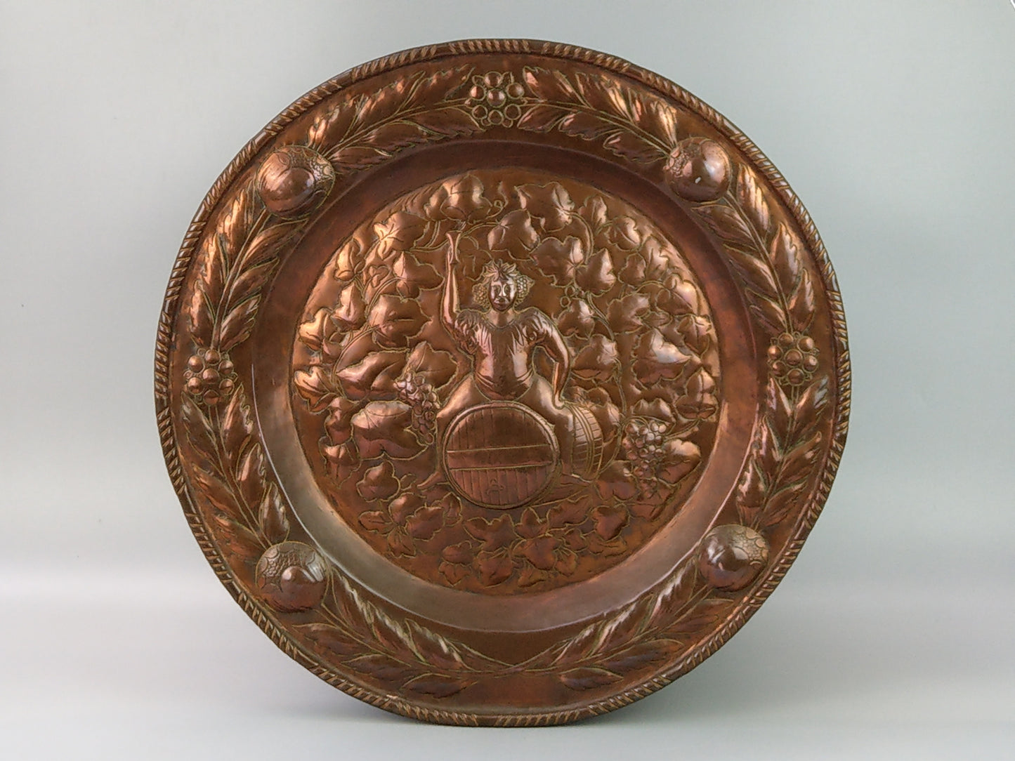 Large arts and crafts copper plaque Bacchus on the barrel with poppies wreath c.1900