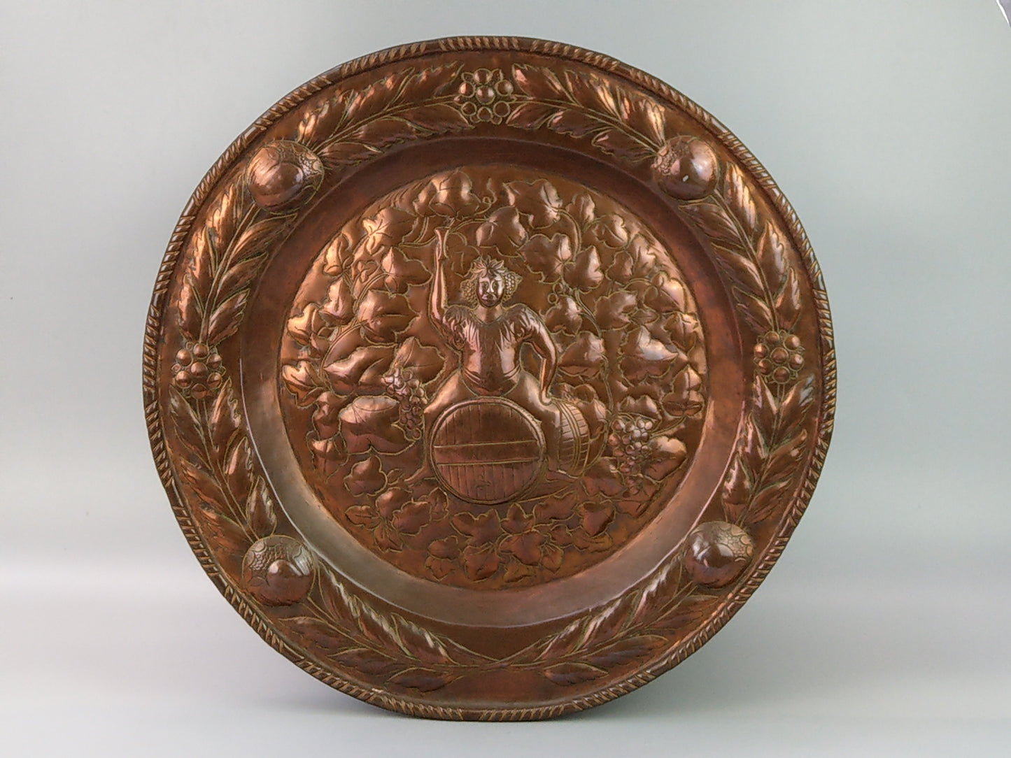 Large arts and crafts copper plaque Bacchus on the barrel with poppies wreath c.1900