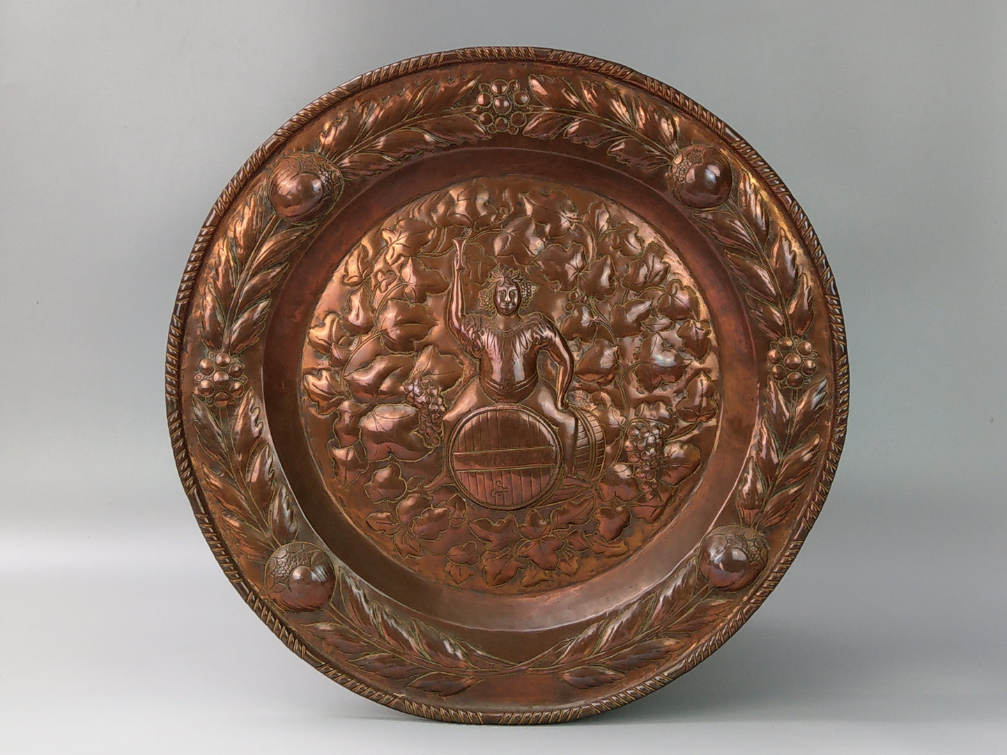 Large arts and crafts copper plaque Bacchus on the barrel with poppies wreath c.1900