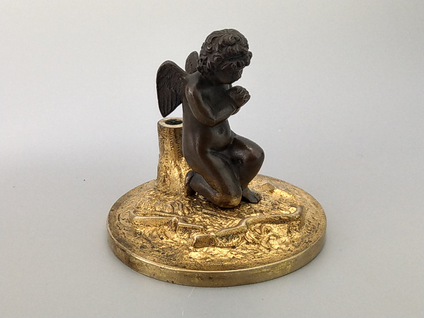 Antique Bronze Putto praying with a broken bow on a gold gild stand