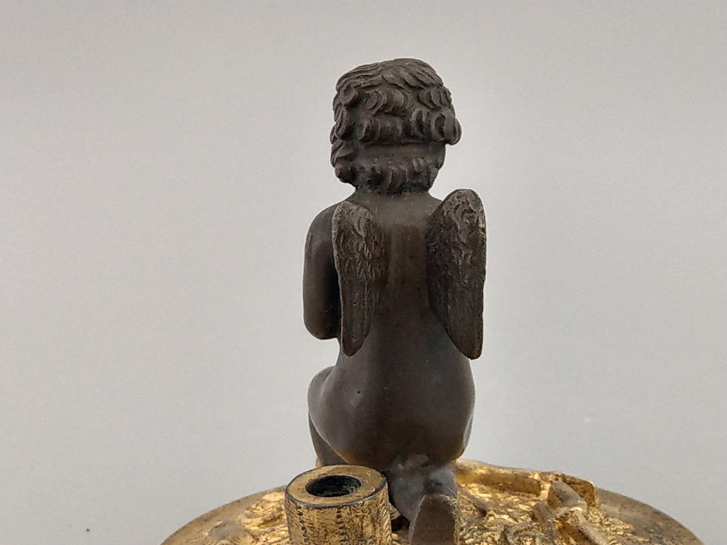 Antique Bronze Putto praying with a broken bow on a gold gild stand