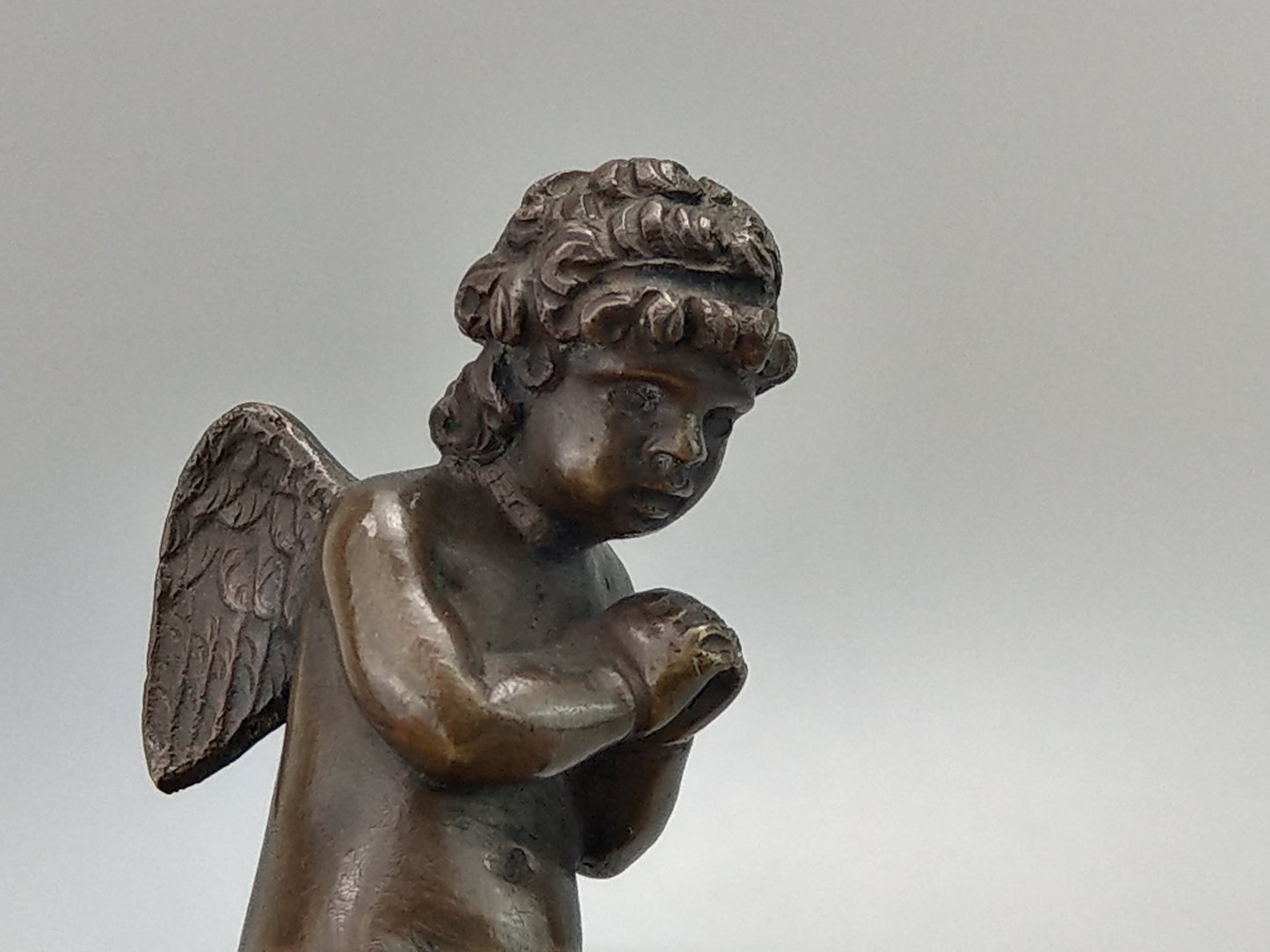 Antique Bronze Putto praying with a broken bow on a gold gild stand