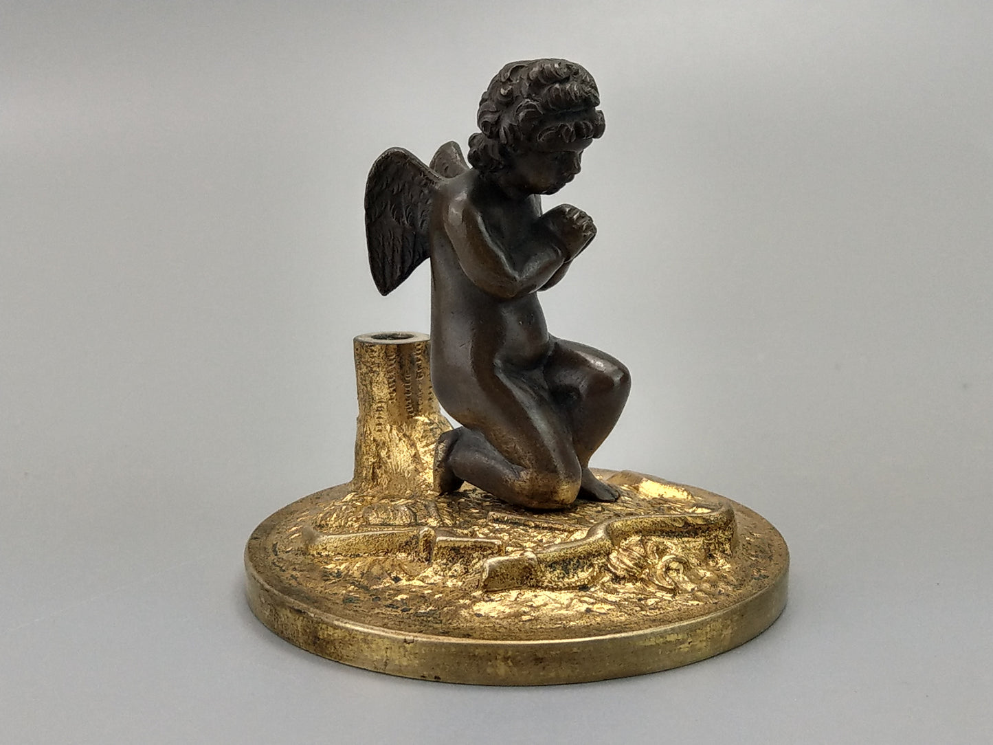 Antique Bronze Putto praying with a broken bow on a gold gild stand